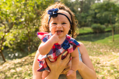 Portrait of a smiling girl holding baby outdoors