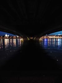 Illuminated bridge over water at night