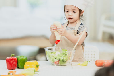 Portrait of girl holding food on table