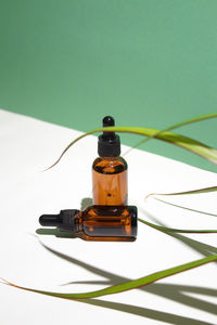 Amber glass dropper bottles different sizes with leaves on white green background. hyaluronic acid 