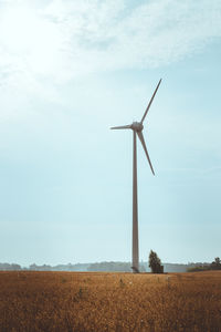 Windmills on field against sky