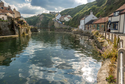 River amidst buildings and mountains against sky