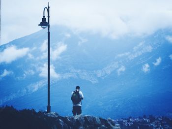 Rear view of man looking at mountains against sky