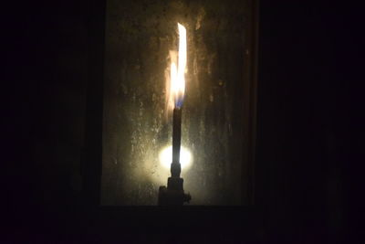 Close-up of lit candle in darkroom