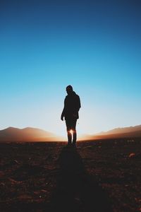 Silhouette of woman standing on landscape against clear sky