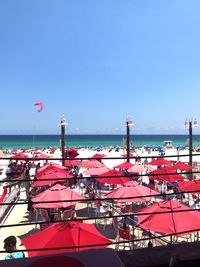 Traditional windmill by sea against clear blue sky
