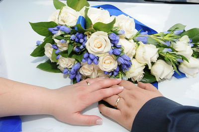 High angle view of couple hands by bouquet at wedding