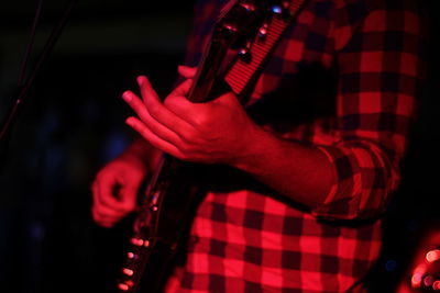 Midsection of man playing guitar at nightclub