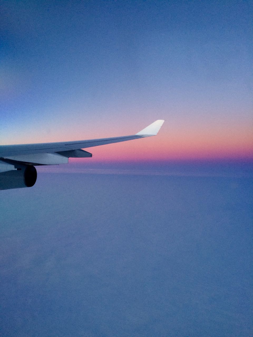 CLOSE-UP OF AIRPLANE WING AGAINST CLEAR SKY DURING SUNSET