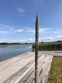 Wooden posts on lake against sky