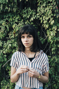 Portrait of young woman standing against plants