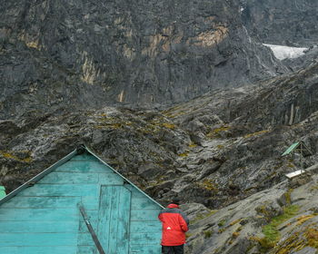Rear view of person standing against house and mountain
