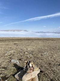 Stack of stones on field against sky