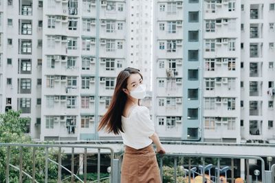 Full length of woman standing against buildings in city