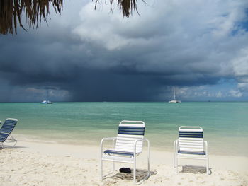 Chairs on beach against sky