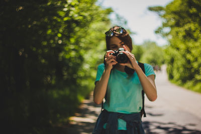 Young woman photographing on road