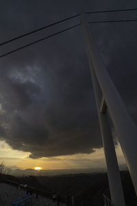 Low angle view of bridge against dramatic sky