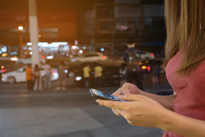 Midsection of woman using mobile phone on street