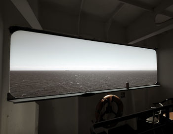 Man by sea against clear sky seen through window