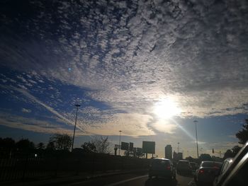 Cars on road in city against sky during sunset