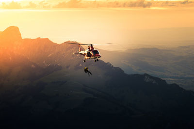 Silhouette man jumping from helicopter