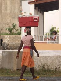 Rear view of young woman standing against built structure