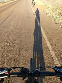 Shadow of man riding bicycle on road