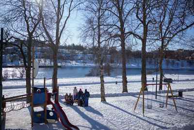 People sitting on snow covered riverbank