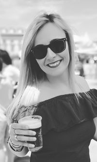 Portrait of young woman wearing sunglasses while having drink during party