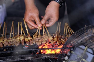 Midsection of man preparing food on barbecue grill