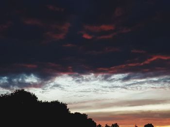 Low angle view of silhouette trees against dramatic sky