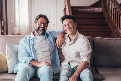 Portrait of smiling father and son sitting on sofa