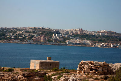 Scenic view of sea and cityscape against clear sky