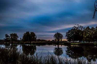 Reflection of trees in lake at sunset