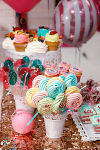 Multicolored meringue on a stick, decorated with multicolored pastry beads on a blurred background