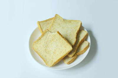 Close-up of bread in plate against white background