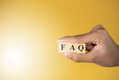 Close-up of person hand with text against yellow background