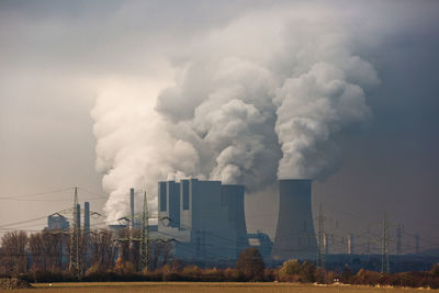 Smoke emitting from factory against sky