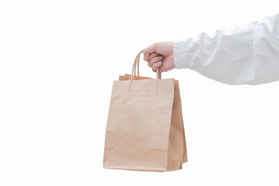 Close-up of hand holding paper over white background