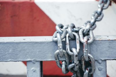 Close-up of chain tied up on metallic railing