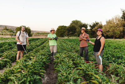 Rear view of women standing by plants against clear sky