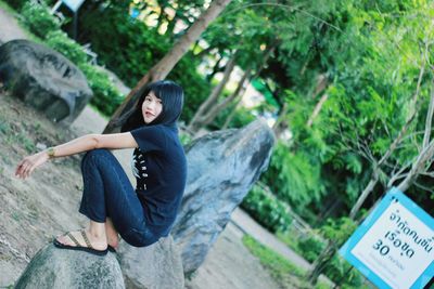 Portrait of young woman sitting on rock