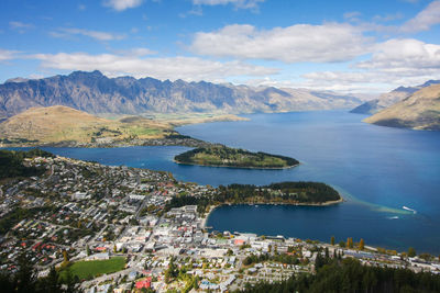 Aerial view of city by sea and mountains against sky