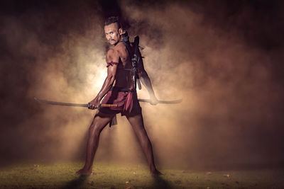 Full length portrait of warrior standing on field at night