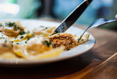 Close-up of person eating pasta with fork and knife