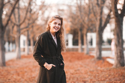 Happy young woman standing with hands in pockets