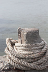 Close-up of rope rolled against lake