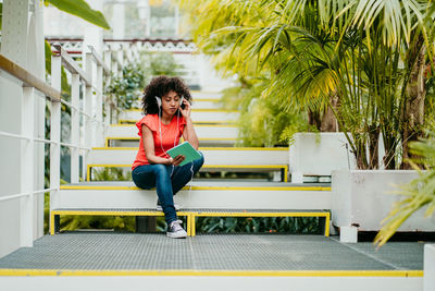 Full length portrait of young woman sitting on bench