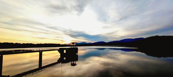 Silhouette bridge over lake against sky during sunset