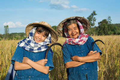 Senior farmer standing with granddaughter on field